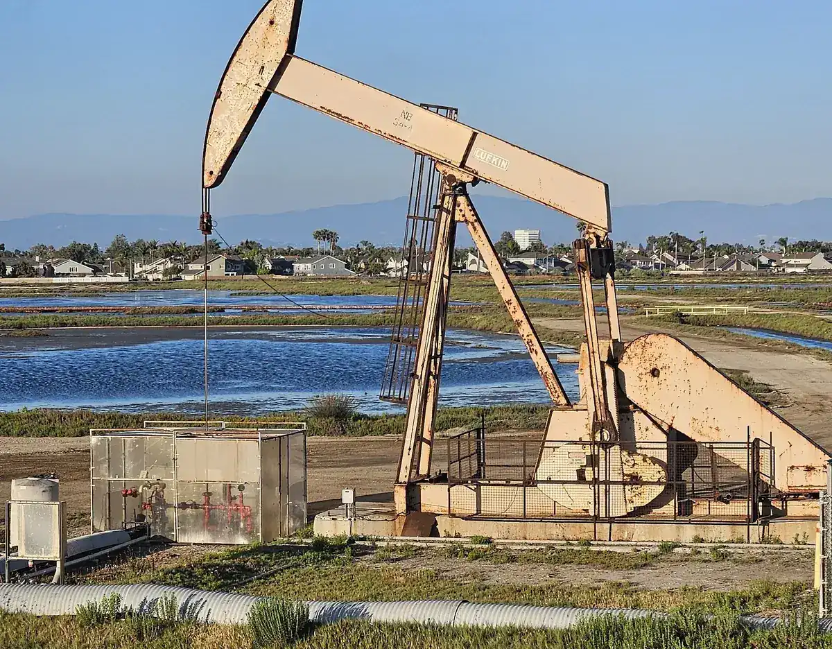 Pumpjack in the Bolsa Chica wetlands with Huntington Beach CA housing behind it