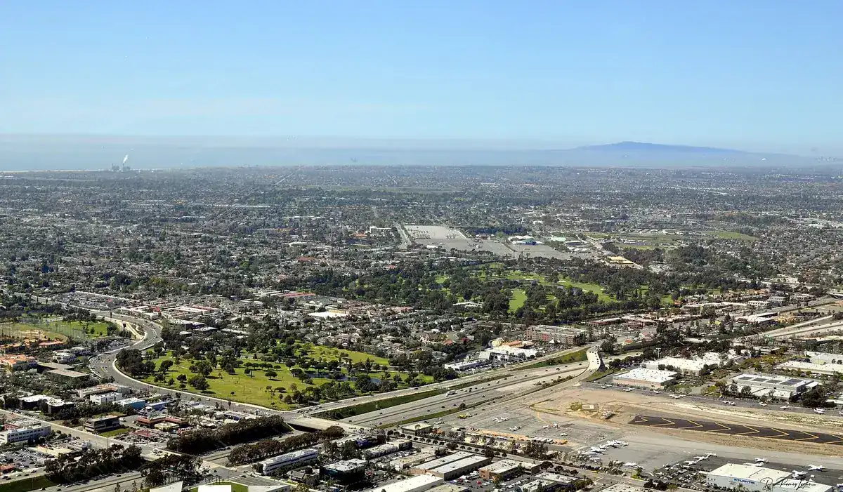 Aerial view over Costa Mesa CA showing housing, a golf course, the freeway and John Wayne Airport