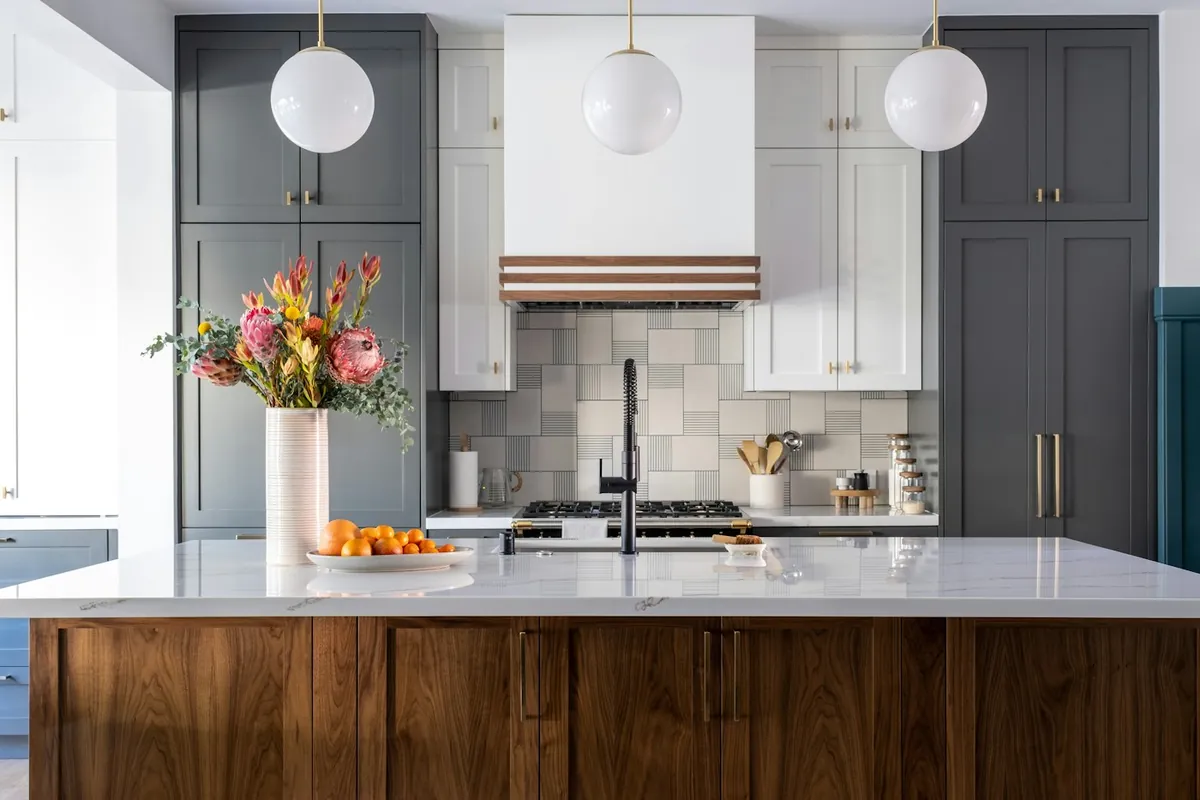 A walnut fronted run with dark green tall cabinets in a Southern California kitchen