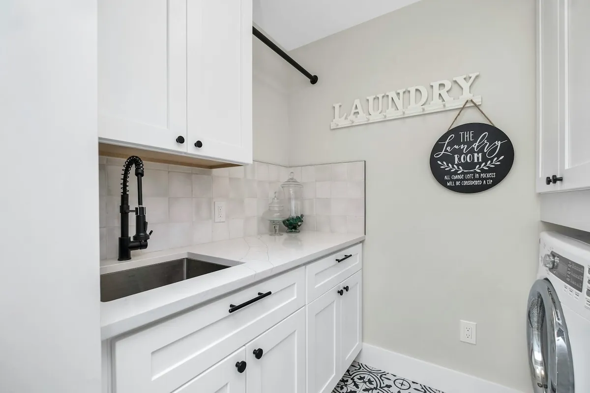 White shaker laundry cabinets with a quartz top and undermount utility sink in a Huntington Beach CA home