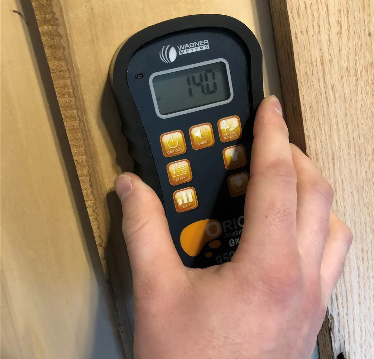 Pinless moisture meter reading 14.0 percent on a wood board before cabinet work in Huntington Beach CA