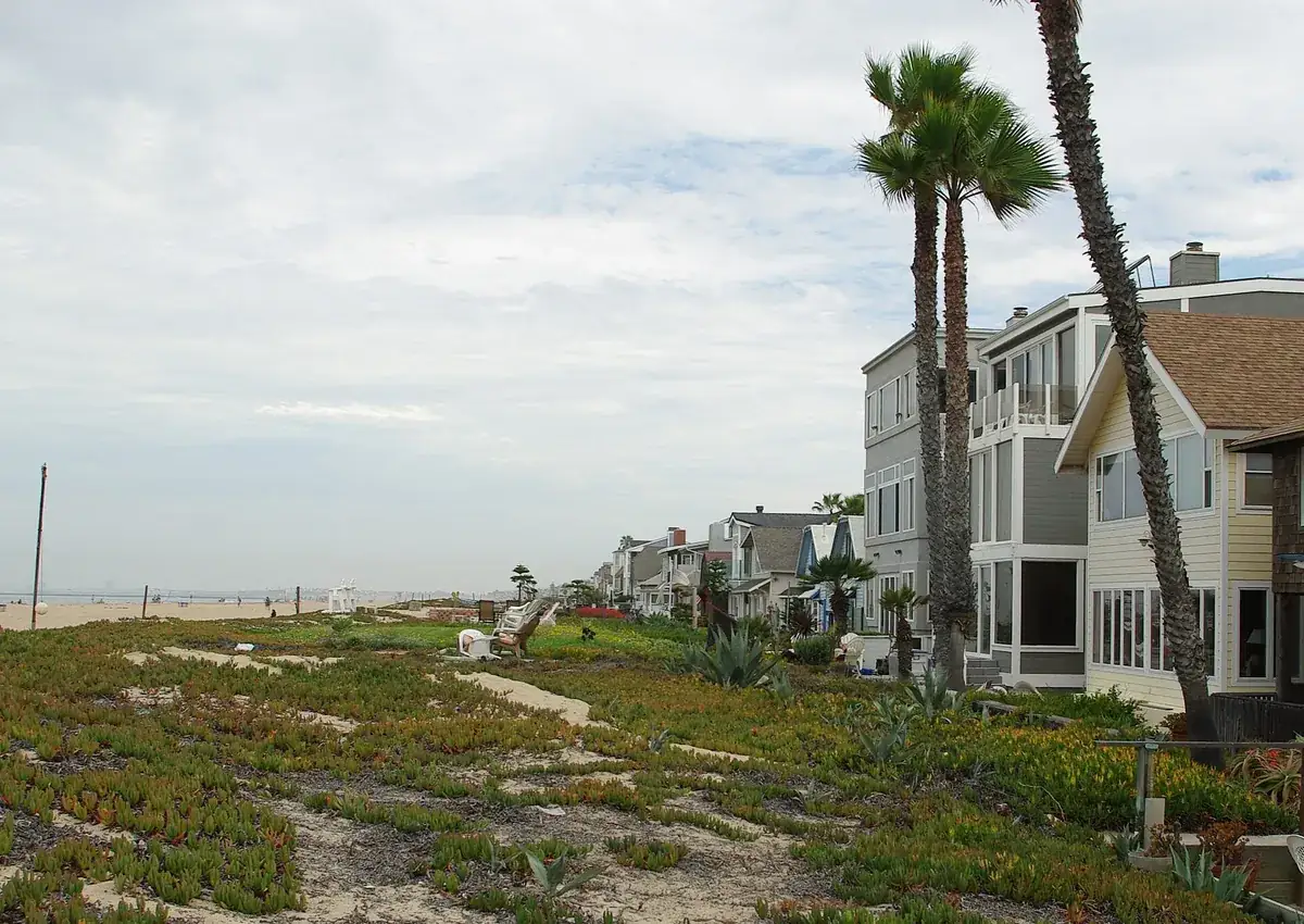 Tall beachfront houses behind dune planting at Sunset Beach in Huntington Beach CA