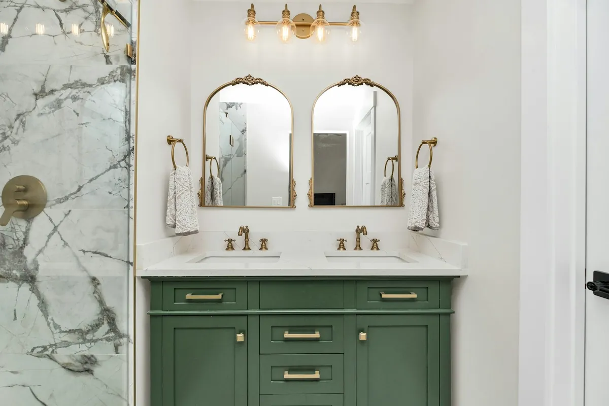 Painted green bathroom vanity with brass hardware and a stone top in a Huntington Beach CA bathroom